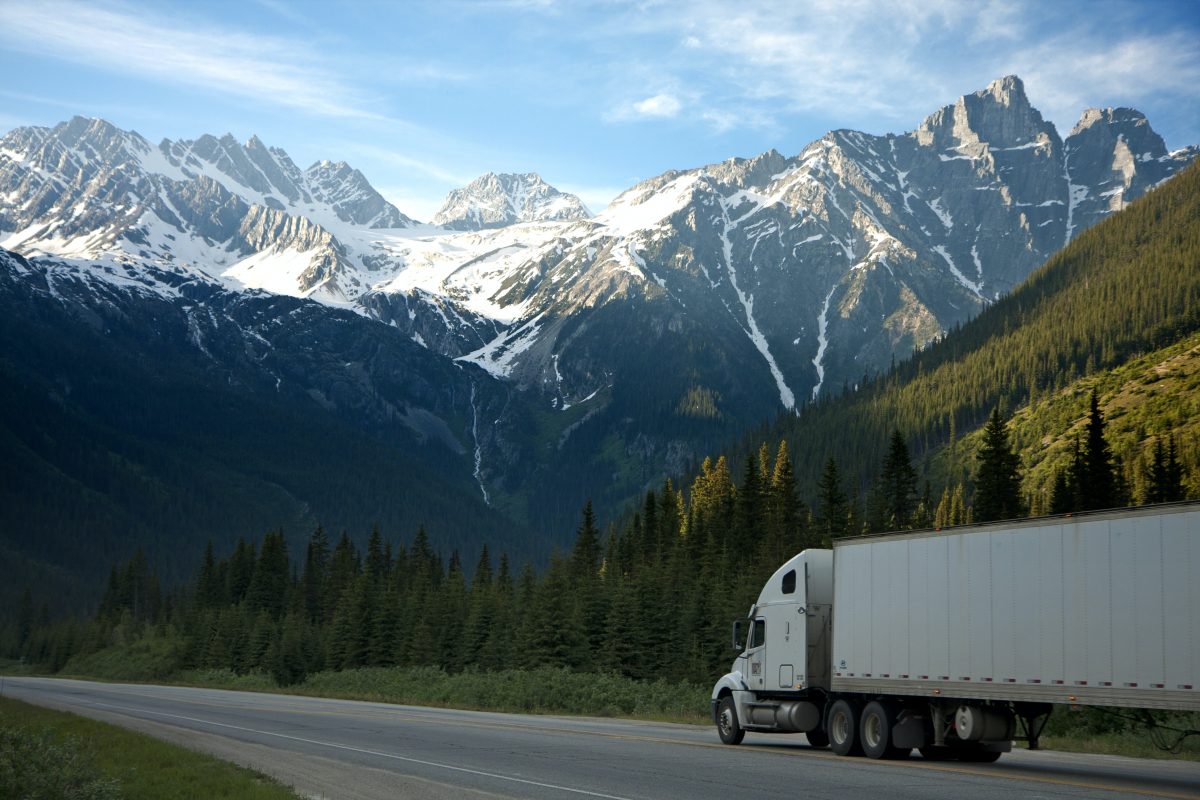 White lorry driving on a road in the mountains for international delivery